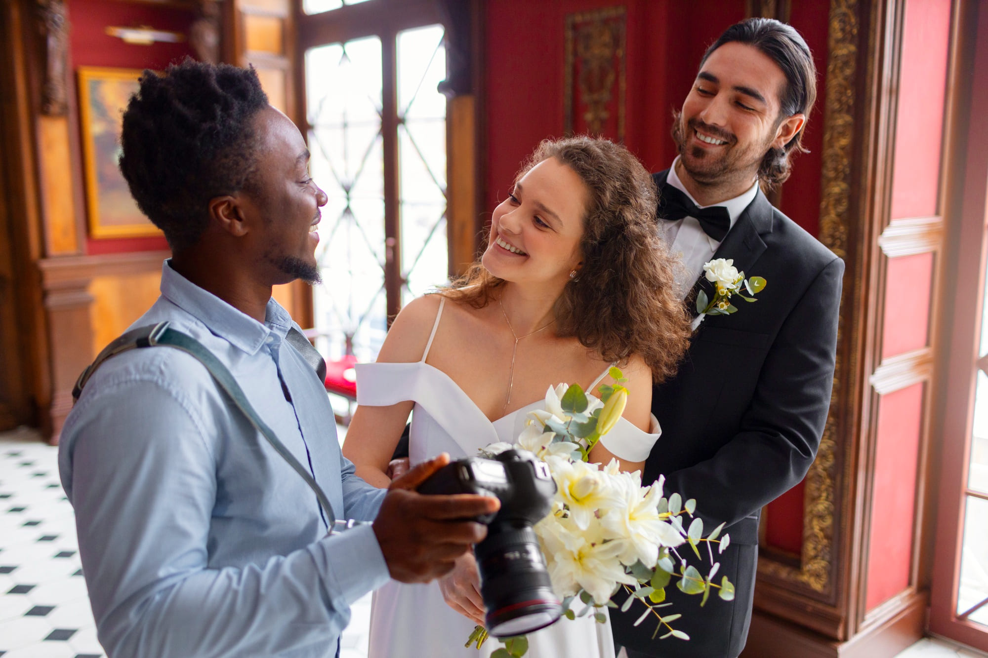 Wedding couple smiling with photographer indoors